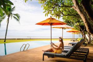 a woman sitting on a bench reading a book next to a pool at Fisherman's Resort Haad Chao Samran in Haad Chao Samran