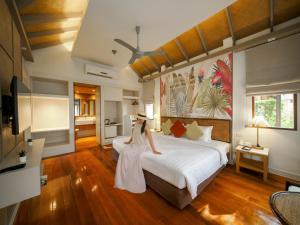 a woman in a white dress standing next to a bed at Fisherman's Resort Haad Chao Samran in Haad Chao Samran