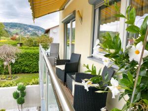 a balcony with chairs and flowers on a house at Appartementhaus Elfi in Barnbach