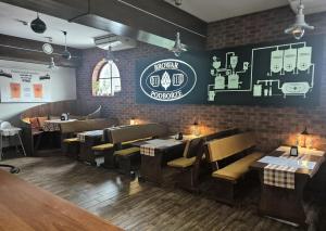 a restaurant with wooden tables and chairs and a brick wall at Dworek Nad Stawem & Łaźnia Piwna in Ostrów Mazowiecka +128 photos