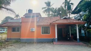 a small orange house with palm trees in the background at Jas Grand Homes in Cochin