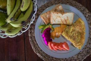 a plate of food with toast and fruit on a table at Suzi Beach House Mentawai in Tua Pejat
