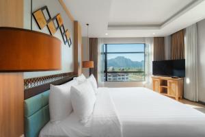 a hotel room with a bed with a large window at Amari Vang Vieng in Vang Vieng