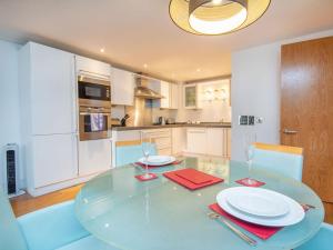 a kitchen with a glass table with plates and glasses at 208 By The Bridge Apartment in Inverness