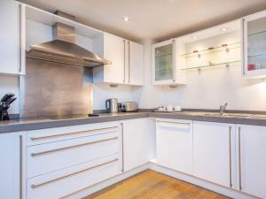 a kitchen with white cabinets and a sink at 208 By The Bridge Apartment in Inverness +6 photos