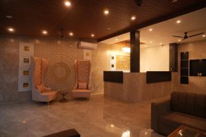 a lobby with two chairs and a counter in a room at Ramjay Corbet Jungle Resort in Kotdwāra