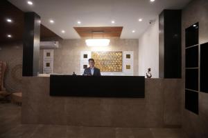 a woman standing at a counter in a lobby at Ramjay Corbet Jungle Resort in Kotdwāra