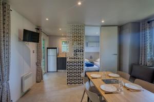 a dining room with a table and a living room at Camping Le Bosquet in Domme