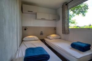 two beds in a small room with a window at Camping Le Bosquet in Domme