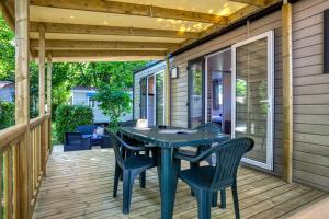 a patio with a table and chairs on a deck at Camping Le Bosquet in Domme