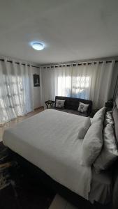 a large white bed in a bedroom with curtains at Palma Spaces in Pretoria