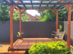 a wooden pergola with a chair on a patio at Palma Spaces in Pretoria