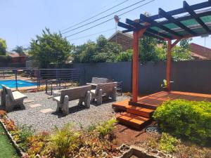 a patio with benches and a wooden pergola at Palma Spaces in Pretoria