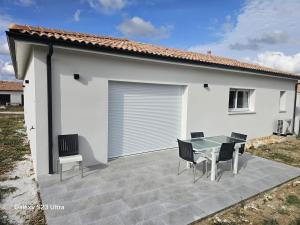 a patio with a table and chairs in front of a house at Relax & work à Frespech 3 chambres 6 personnes in Frespech
