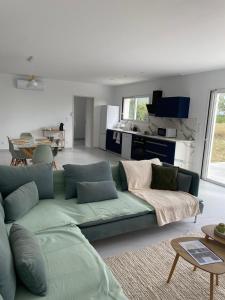 a living room with a green couch and a kitchen at Relax & work à Frespech 3 chambres 6 personnes in Frespech