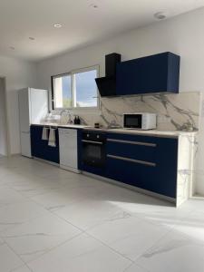 a kitchen with blue cabinets and a marble counter top at Relax & work à Frespech 3 chambres 6 personnes in Frespech