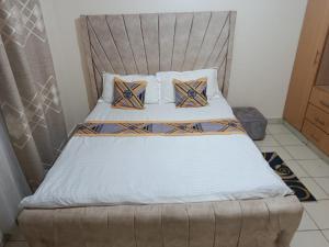 a bedroom with a bed with a headboard and pillows at The ZEN DEN in Eldoret