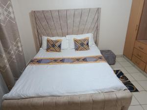 a bedroom with a bed with a headboard and pillows at The ZEN DEN in Eldoret +1 photo