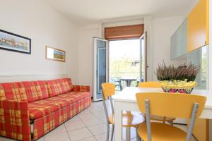 a living room with a couch and a table and chairs at Sunbeach Apartments in Lignano Sabbiadoro