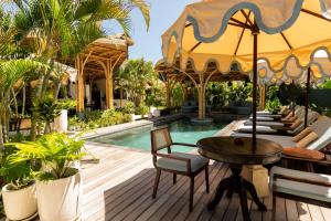 a resort with a pool and a table and chairs at Villa Tokay - The Luxury Resort in Gili Islands