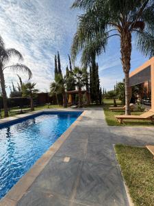 a swimming pool with palm trees next to a house at Villa Sofia And Spa in Marrakesh