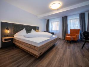 a bedroom with a large bed and a chair at Pension Kohler in Fügen