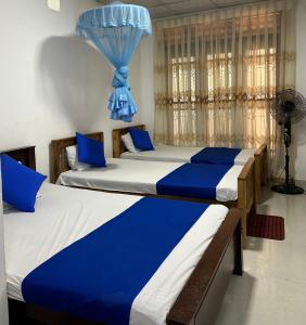 two beds in a room with blue and white at LOTUS HOLIDAY REST in Anuradhapura +3 photos