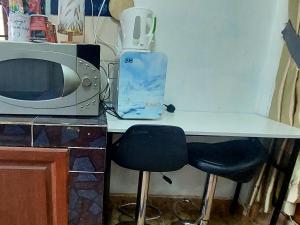 a kitchen table with two chairs and a microwave at Cassa Bonda Single Studio in Kampong Bakat