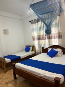two beds in a room with blue curtains at LOTUS HOLIDAY REST in Anuradhapura