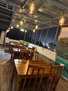 a restaurant with wooden tables and chairs and windows at Hotel The Rajputana Ranthambore in Sawāi Mādhopur