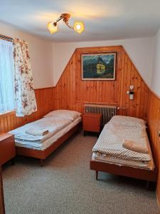 two beds in a room with wood paneling at ZorHouse Ždiar in Ždiar