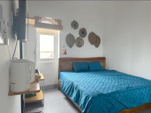 a bedroom with a bed with blue sheets and a window at 49homestay in Ấp Khánh Phước (1)
