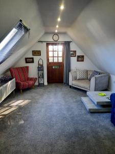 a attic living room with a couch and a clock at The Barn at Creech View in Wareham