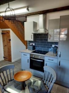 a kitchen with a stove and a table with chairs at The Barn at Creech View in Wareham