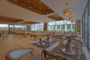 a restaurant with tables and chairs and windows at Sterling Avante Chandigarh Mohali in Mohali