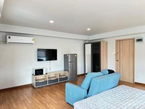 a living room with a blue couch and a television at Msthouse in Ban Bang Phun