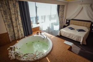 eine Badewanne in einem Zimmer mit einem Bett in der Unterkunft Spa Hotel Meliot in Tscheljabinsk