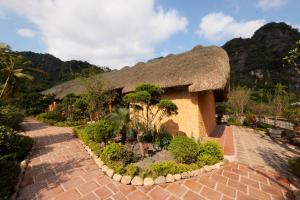 a building with a thatched roof with a garden at The Bổi Heritage Tam Coc in Ninh Binh