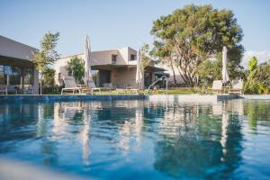 a swimming pool with chairs and a house at Helichrysum Lofts Junior House J1 in Khokhlastí