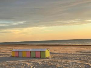 a colorful beach shack on the beach at sunset at Appartement spacieux rénové, vue mer - 2 chambres in Berck-sur-Mer