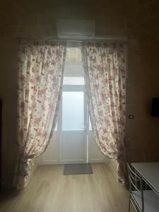 a window with curtains in a room with wooden floors at Casa vacanze da Savio in Trani +1 photo