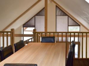 ein Holztisch mit Stühlen in einem Zimmer mit Fenstern in der Unterkunft Campbell Lodge in Thorpe on the Hill