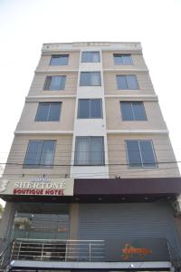 a tall tan building with a store front at Hotel Jaipur Shertone in Jaipur