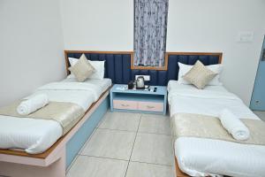 a room with two beds and a side table at Hotel Shree Niwas Inn Near Airport in Jāmb
