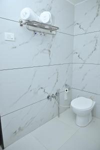 a bathroom with white marble walls and a toilet at Hotel Shree Niwas Inn Near Airport in Jāmb +11 photos