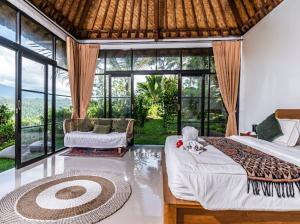 a bedroom with a bed and a couch and windows at Ritual Ubud in Gianyar