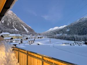 a village covered in snow with mountains in the background at Ari Apartment Wald am Arlberg in Wald am Arlberg