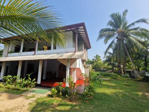 a man on a balcony of a house with a palm tree at Mango Lodge in Aluthgama