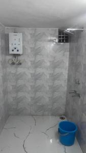 a bathroom with a tiled wall with a blue bucket at Full Moon Home Stay in Jamania