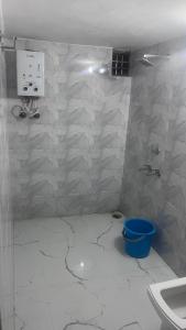 a bathroom with white marble walls and a blue bucket at Full Moon Home Stay in Jamania